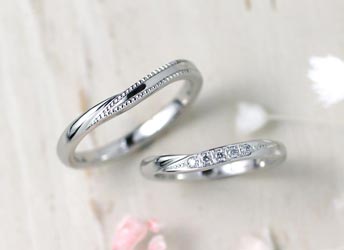 互い違いに重なった腕にダイヤとミル打ちの手作り結婚指輪
